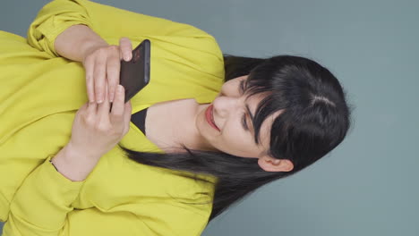 Vertical-video-of-The-woman-looking-at-the-phone-is-happy.